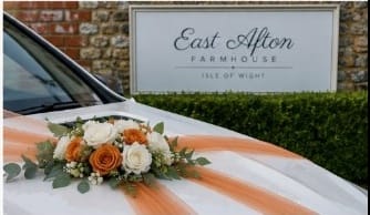 The car dressed with peach ribbons and flowers outside East Afton Farmhouse, Isle of Wight